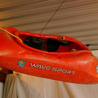 A red kayak hanging from a ceiling inside.
