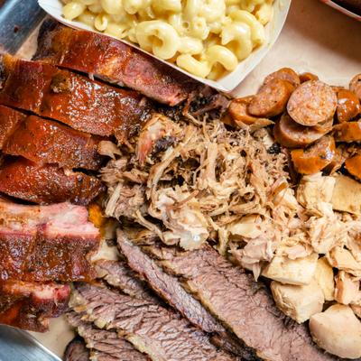 The Meatpocalypse BBQ tray with variety of meats and sides, close-up.