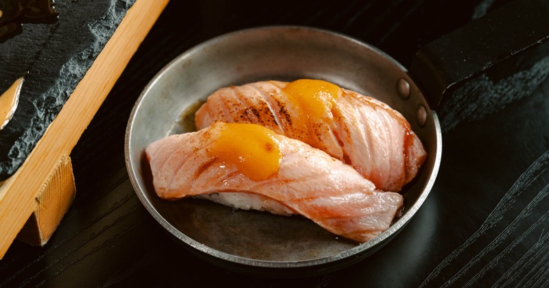 Seared salmon nigiri sushi served in a small skillet