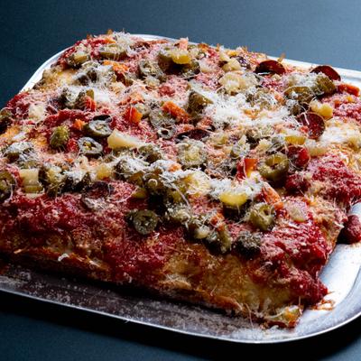 Square focaccia pizza topped with tomato sauce, grated cheese, and pickled jalapenos.