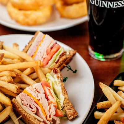 Club sandwich with fries and a glass of dark beer.
