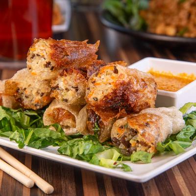 Crispy fried spring rolls on greens with dipping sauce.