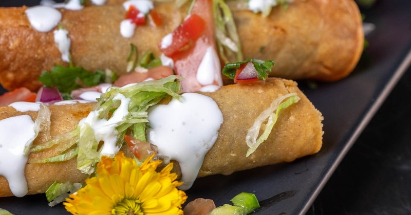 Flautas, topped with tomato, lettuce, and sauce