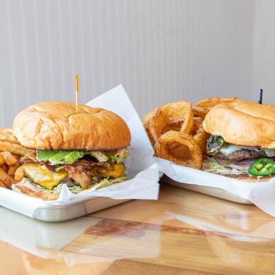 Two cheeseburgers served with fries and onion rings.