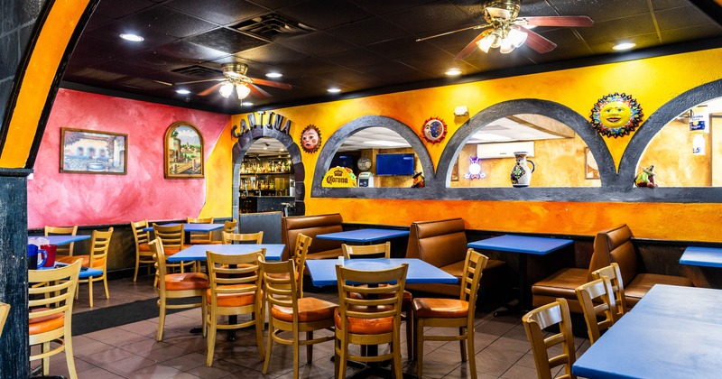 Colorful Mexican restaurant interior with vibrant orange and pink walls, wooden chairs