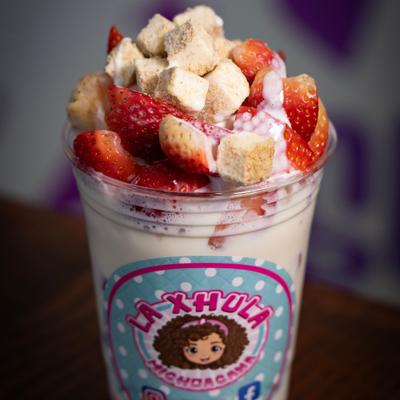Strawberry dessert drink topped with cookie cubes.