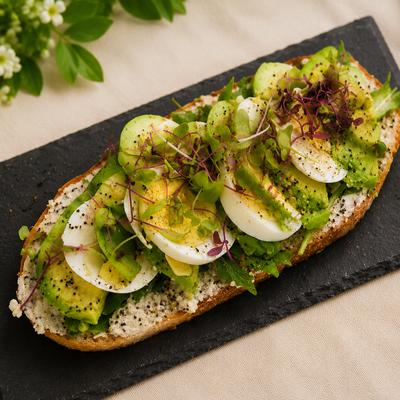 Avocado toast with eggs, microgreens, and dressing.