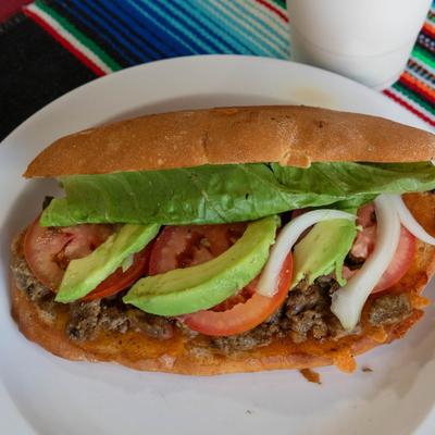 Torta sandwich, with ground beef, lettuce, avocado, onion, and tomato.