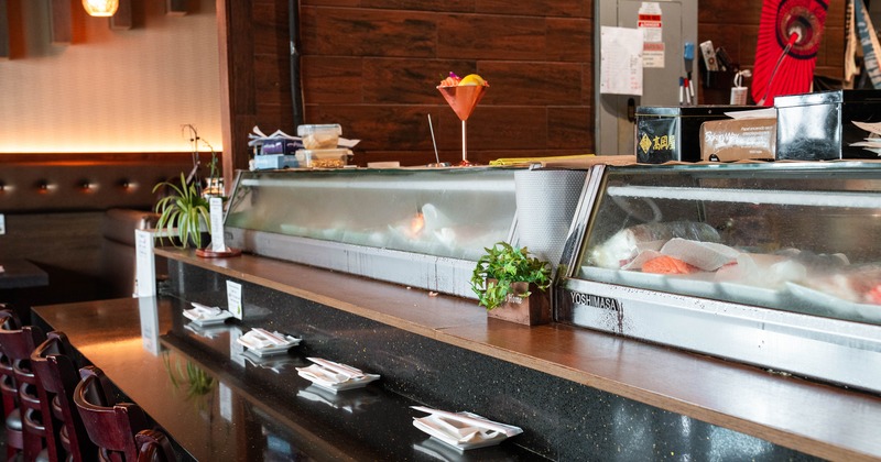 Interior dining area of a Japanese sushi restaurant, counter with plates, chopsticks, and napkins