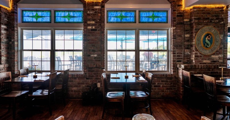 Interior of a restaurant with exposed brick walls, wooden furniture, and stained-glass windows