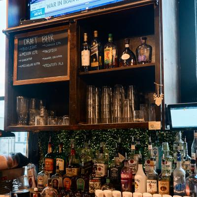 Well-stocked bar shelves with various bottles, glasses and a chalkboard menu.