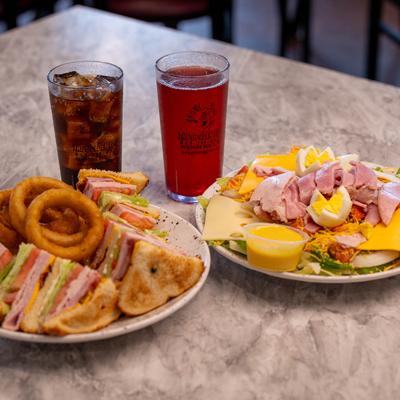 Club sandwich, Chef salad and two glasses of soft drinks.