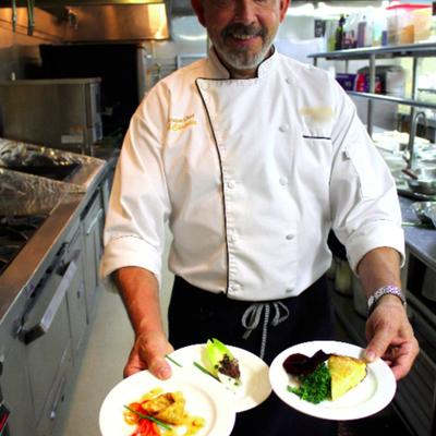 A chef holding several plates of food.