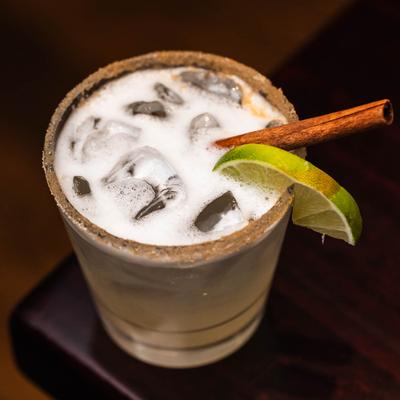Cinnamon pear margarita, garnished with a lime slice and a cinnamon stick.