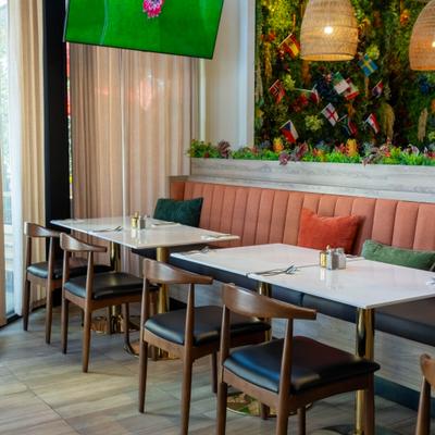 Interior featuring  green foliage decorating the wall and orange plush banquette seating.