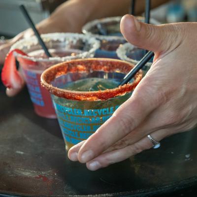 Three small cocktails garnished with a rim of chili-lime salt, placed on a serving tray.