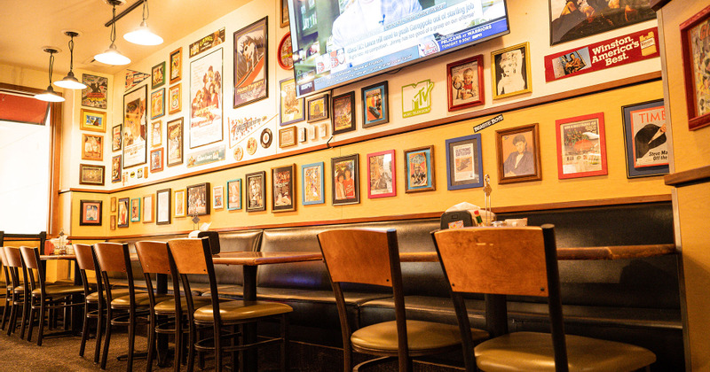 Booths, tables and chairs, large TV screen on the wall