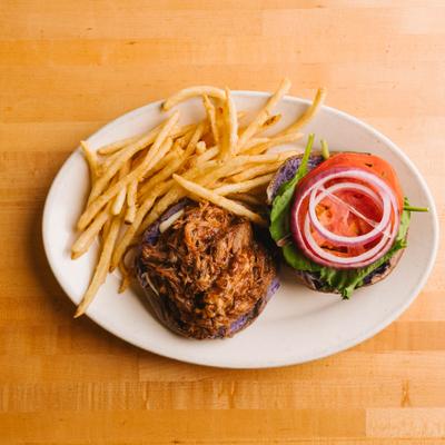 Pulled pork sandwich served alongside fries on a plate.