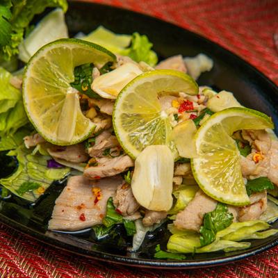 Salad with mixed greens, pork tenderloin, lime, garlic and chili, close-up.