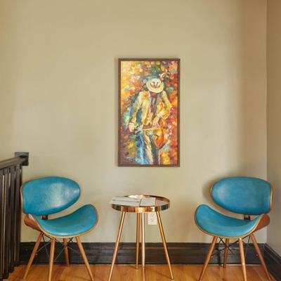 Interior, two blue chairs and a copper coffee table by a tan wall with a painting on it.