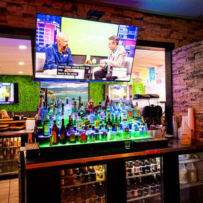 Bar area, various liquor bottles, hanging TV screen.