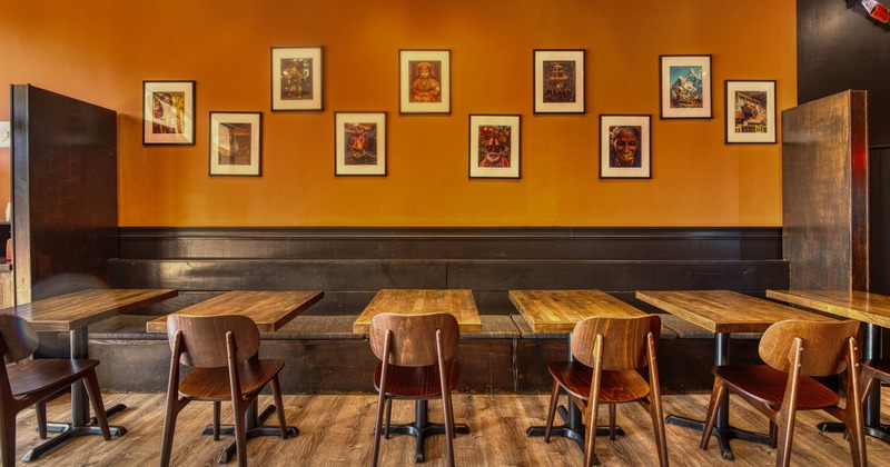 Interior, wooden banquette bench with wooden top tables and chairs, pictures on the wall