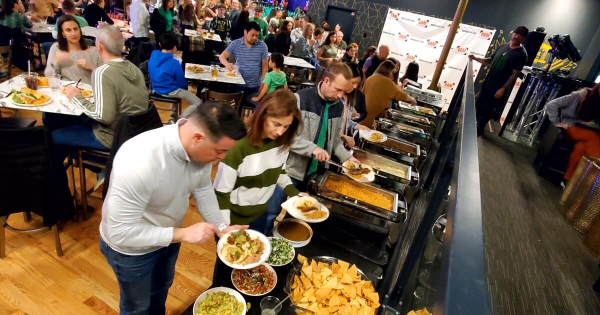 Group of people serving themselves from a buffet line at an indoor catered event