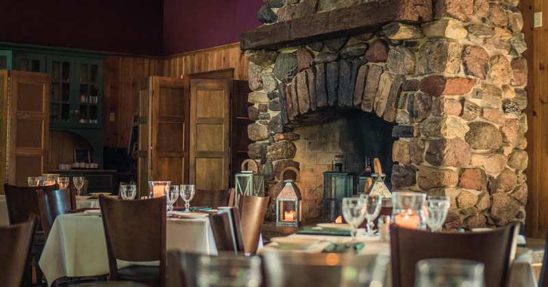 Interior, set tables and seating in a dining area with fireplace
