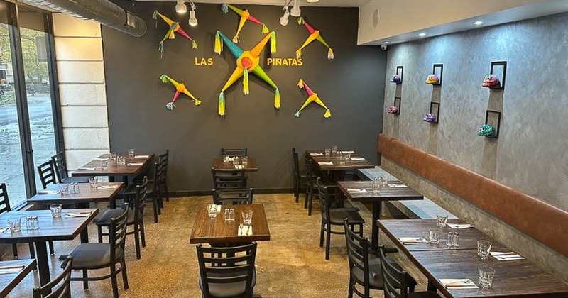Interior with wooden tables, benches for dining and pinatas on the wall