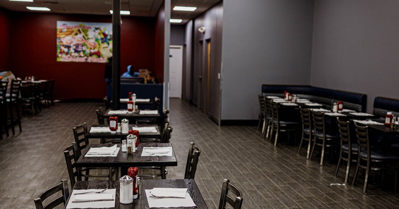 Interior of a modern restaurant with tables and chairs on wood-tiled flooring