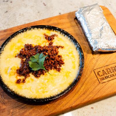 Queso Fundido topped with chorizo and served on a sizzling skillet.