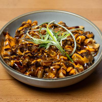 Pork belly fries topped with sauces and green onions.