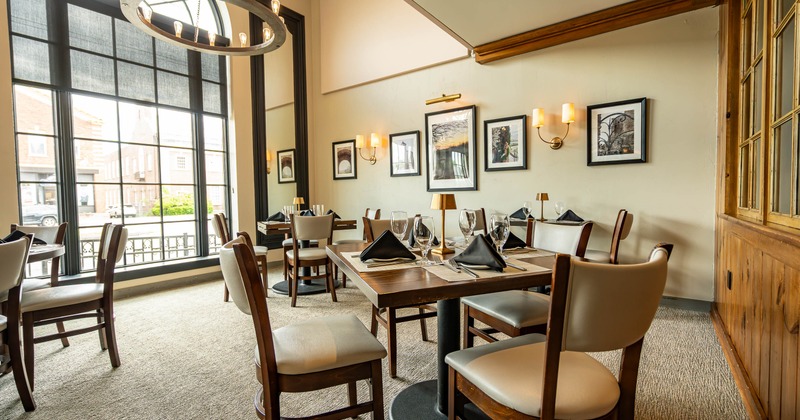 Elegant restaurant interior with wooden tables, cushioned chairs, and black napkins