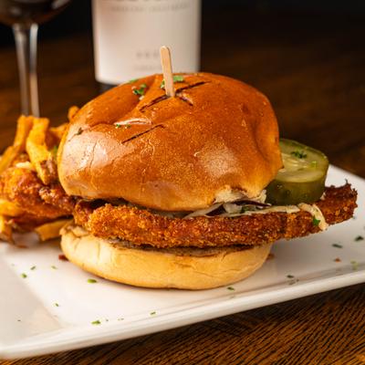 Fried chicken sandwich on a toasted bun with pickles and fries.