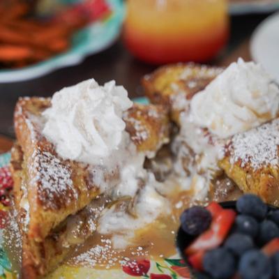 French toast dusted with powdered sugar and topped with whipped cream, served with berries.