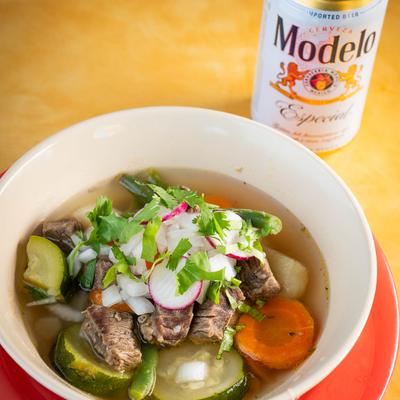 Mexican beef soup bowl and a can of beer.