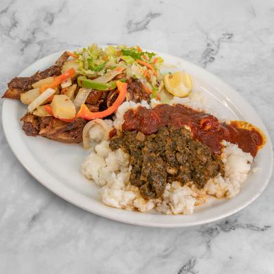 Roasted goat meat served with white rice topped with sauces and a side salad.
