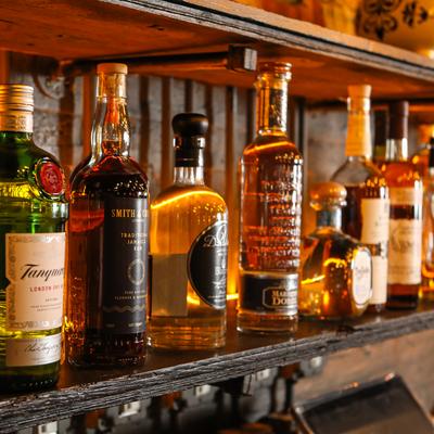 Selection of spirits on a rustic wooden bar shelf, close-up.