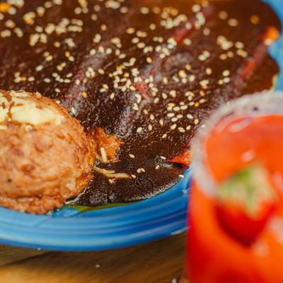 Close-up of enchiladas covered in mole sauce and sesame seeds.