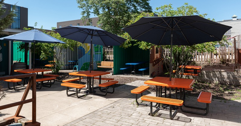 Outdoor seating area with conjoining tables and benches and black parasols