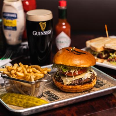 Cheeseburger with fries and pickle served with a pint of Guinness.