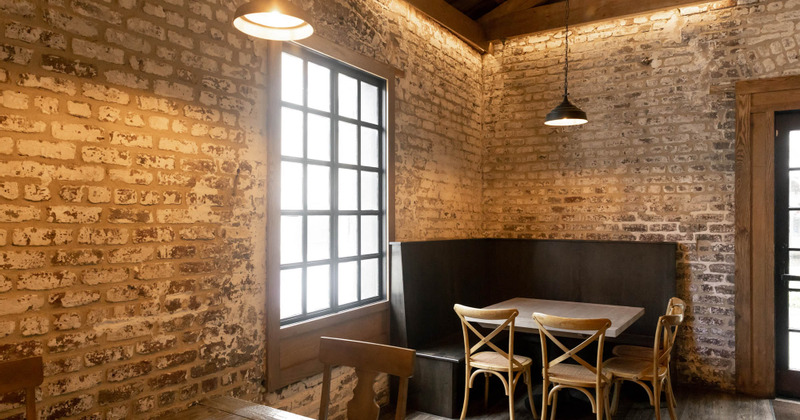 Interior, walls made of bricks, table in the corner by the window