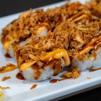 Crunchy California Roll topped with fried onions, close-up.
