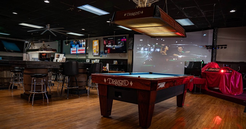 Interior, a pool table with a large projector screen in the back