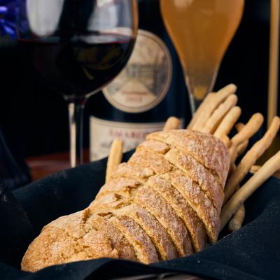 Sliced bread sits on a plate next to wine glasses.