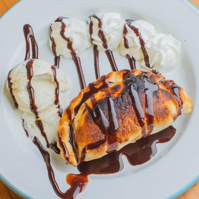 Baked pastry with ice cream, whipped cream, and chocolate drizzle.
