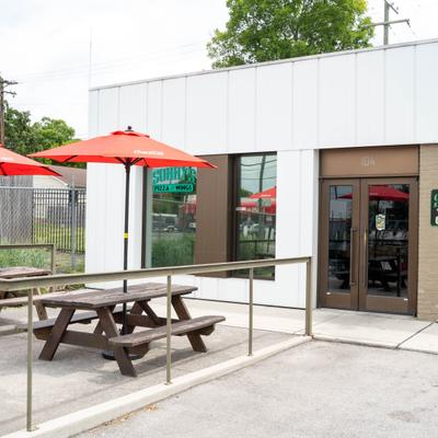 Outdoor patio seating featuring red umbrellas and picnic tables.