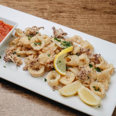 Fried calamari served with lemon slices and tomato sauce.