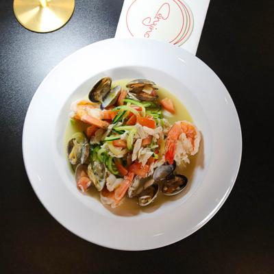 Zucchini pasta with mixed seafood and tomato.