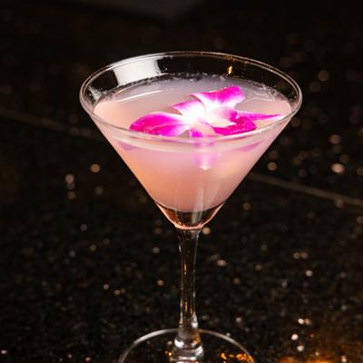 Cosmopolitan served in a martini glass, garnished with a orchid.